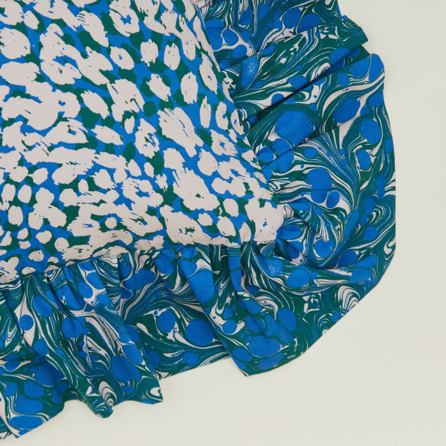 A close up of a ruffled floral cushion with an evergreen pattern.