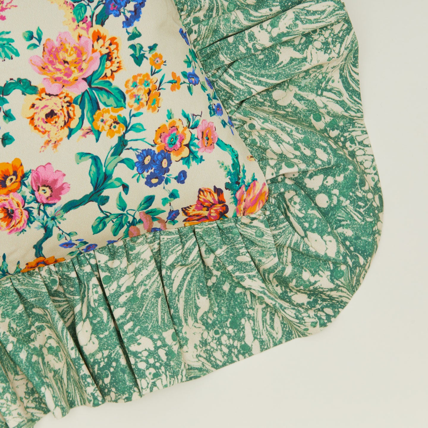 A close up of a ruffled floral cushion with a fern pattern.