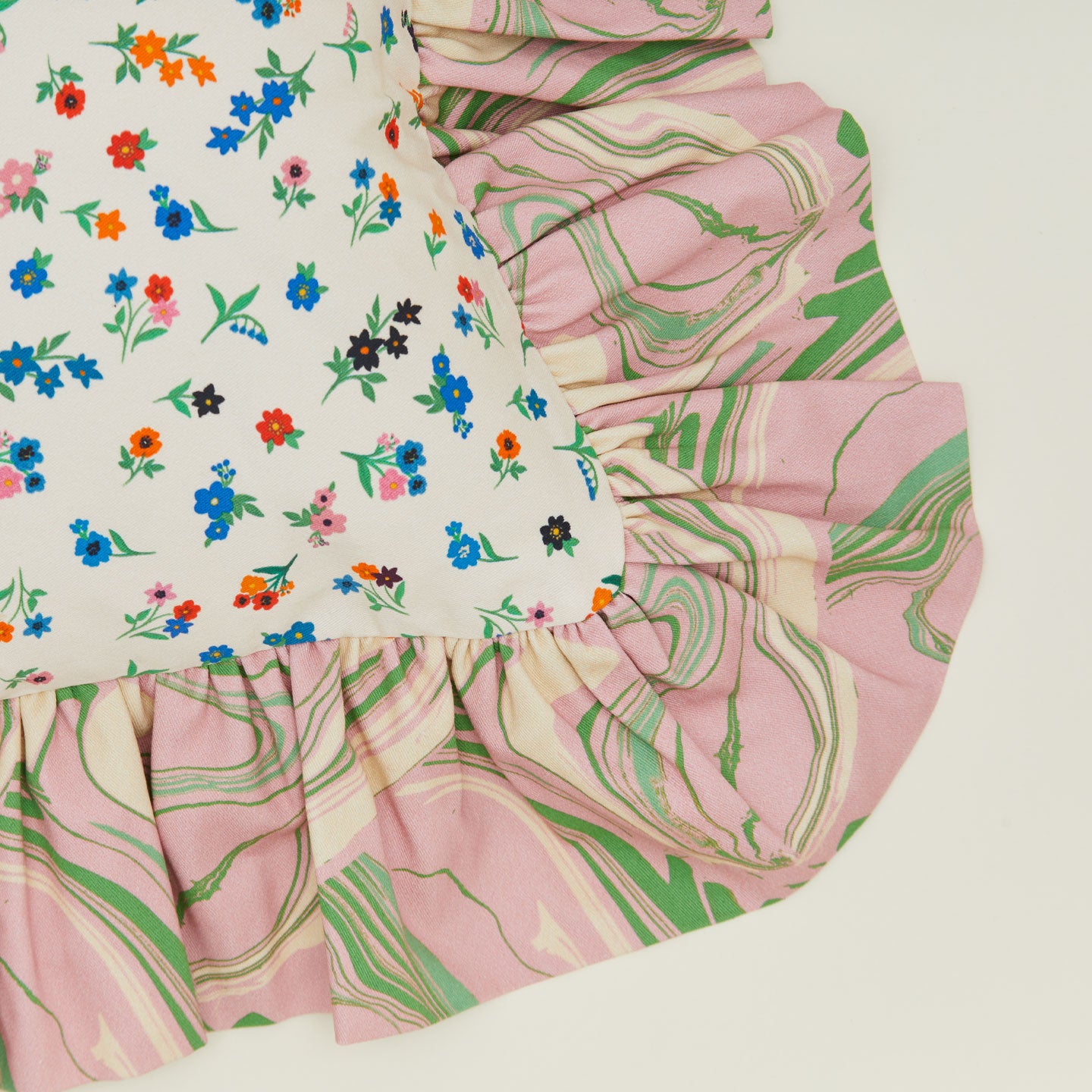 A close up of a ruffled floral cushion with a peony pattern.