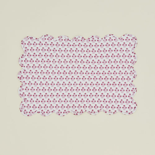 A quilted rectangular placemat with a floral print in Abigail pink.
